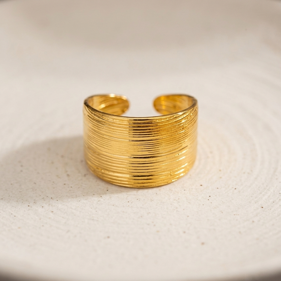 A close-up of 18kt gold plated ring on a textured white surface