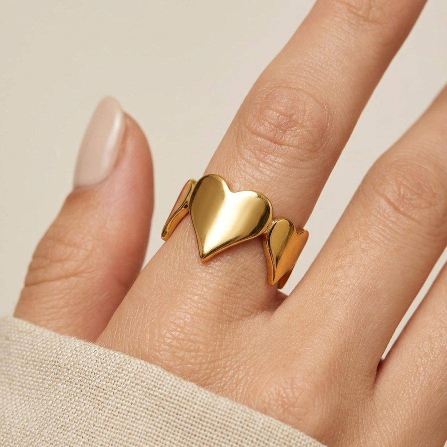 18kt gold plated heart-shaped ring on a finger against a neutral background