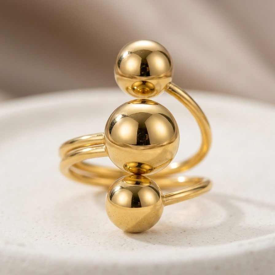 18kt gold plated ring with three spherical elements on a light background