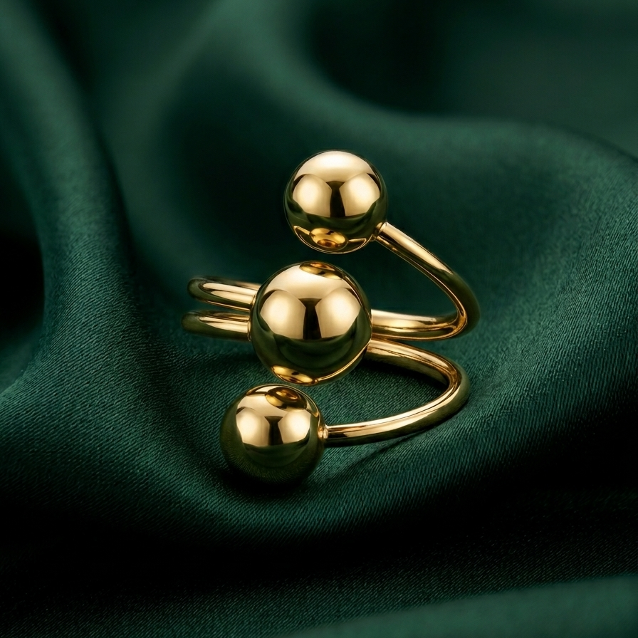 18kt gold plated ring with three spherical elements on a green fabric background