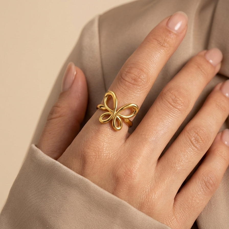 18kt gold plated butterfly ring on a hand with a beige background
