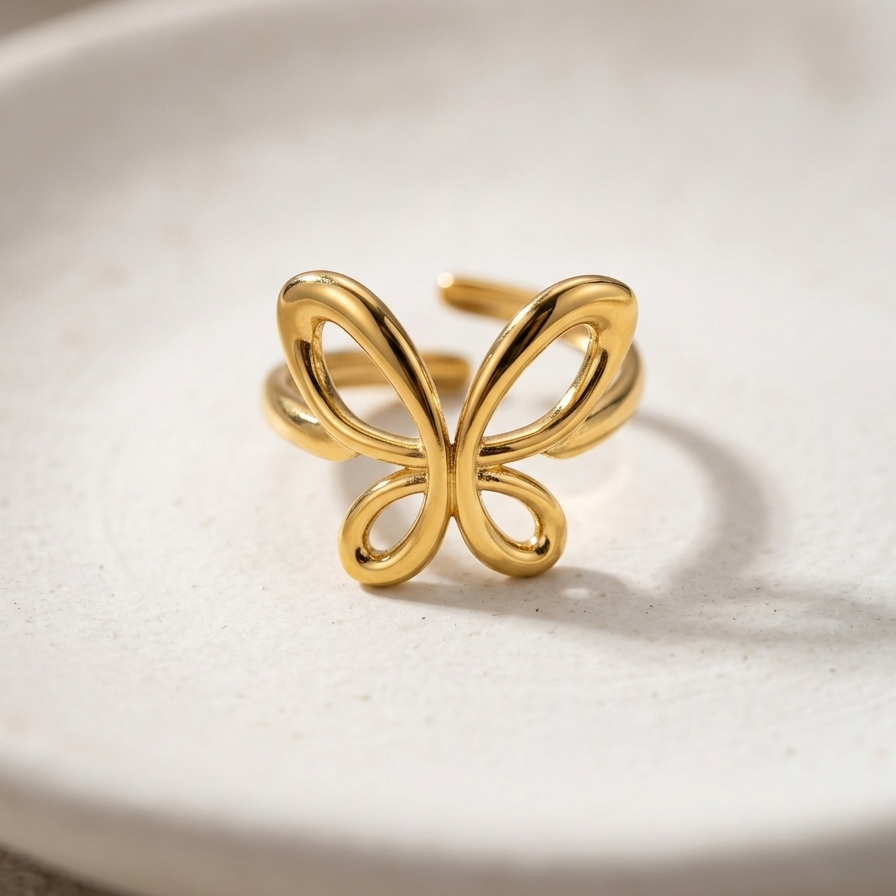18kt gold plated butterfly-shaped ring on a white ceramic plate