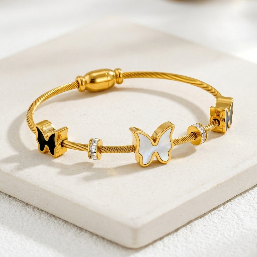 18kt gold plated cable wire magnetic bangle bracelet with black and white butterfly charms on white stone.
