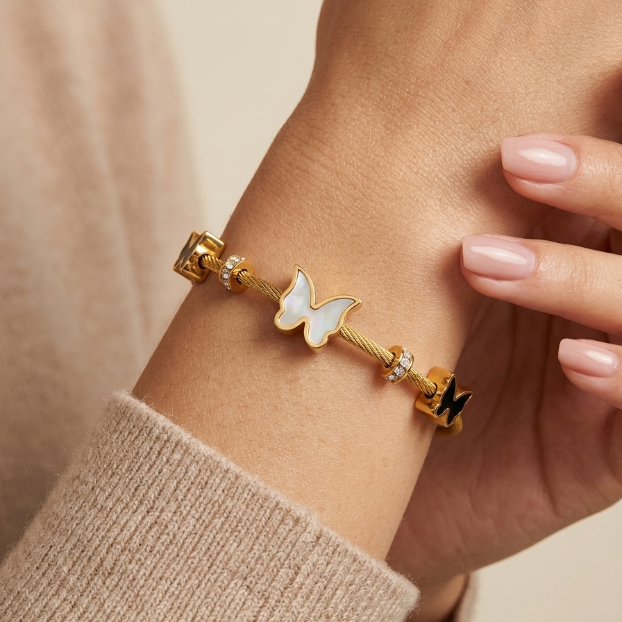 A model worn 18kt gold plated cable wire magnetic bangle bracelet with black and white butterfly charms.