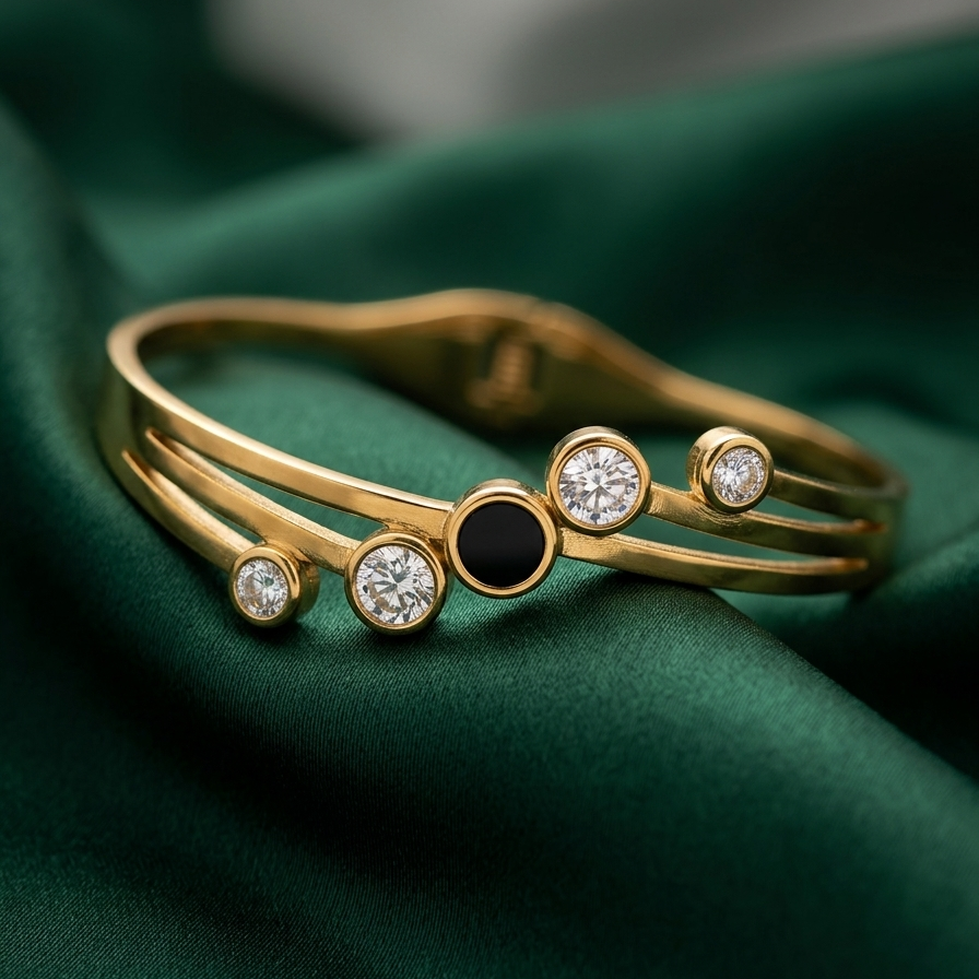 18kt gold plated hinged bangle bracelet with black stone and crystal circles resting on dark green cloth.