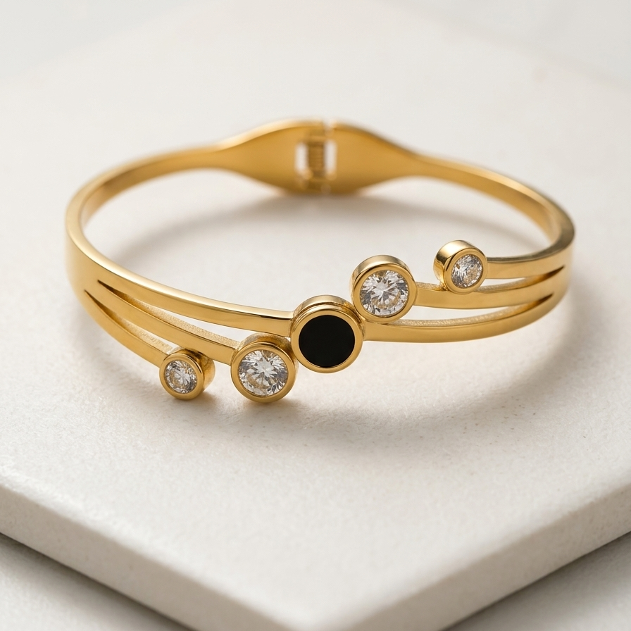 18kt gold plated, waterproof, the onyx crystal orbit bangle bracelet on off-white stone.
