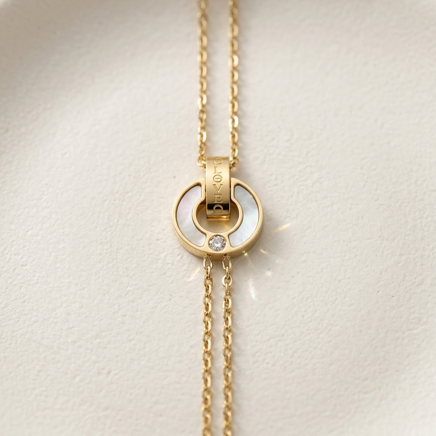 18kt gold plated, anti-tarnish chain bracelet with interlocking circles, mother of pearl inlay and engraved "BELOVED" text on off-white stone background.