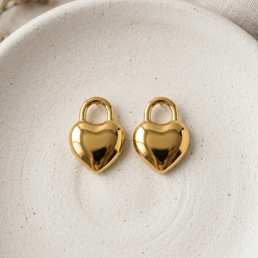 18kt gold plated puffy heart lock earrings on white stone plate.
