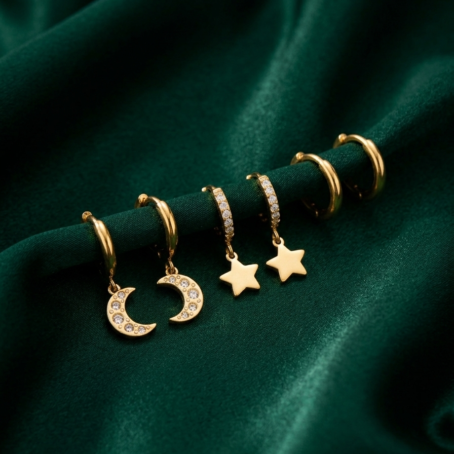 18kt gold plated celestial trio earring set resing on a smooth green fabric.