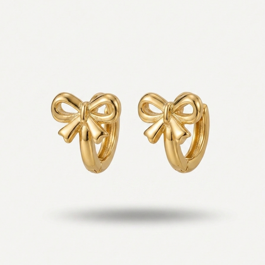 18kt gold plated ribbon bow huggies floating on a white background.