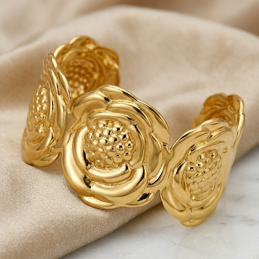 A close-up photography of 18kt gold plated, anti-tarnish wide cuff bracelet with sculpted camellia flower design on beige background.