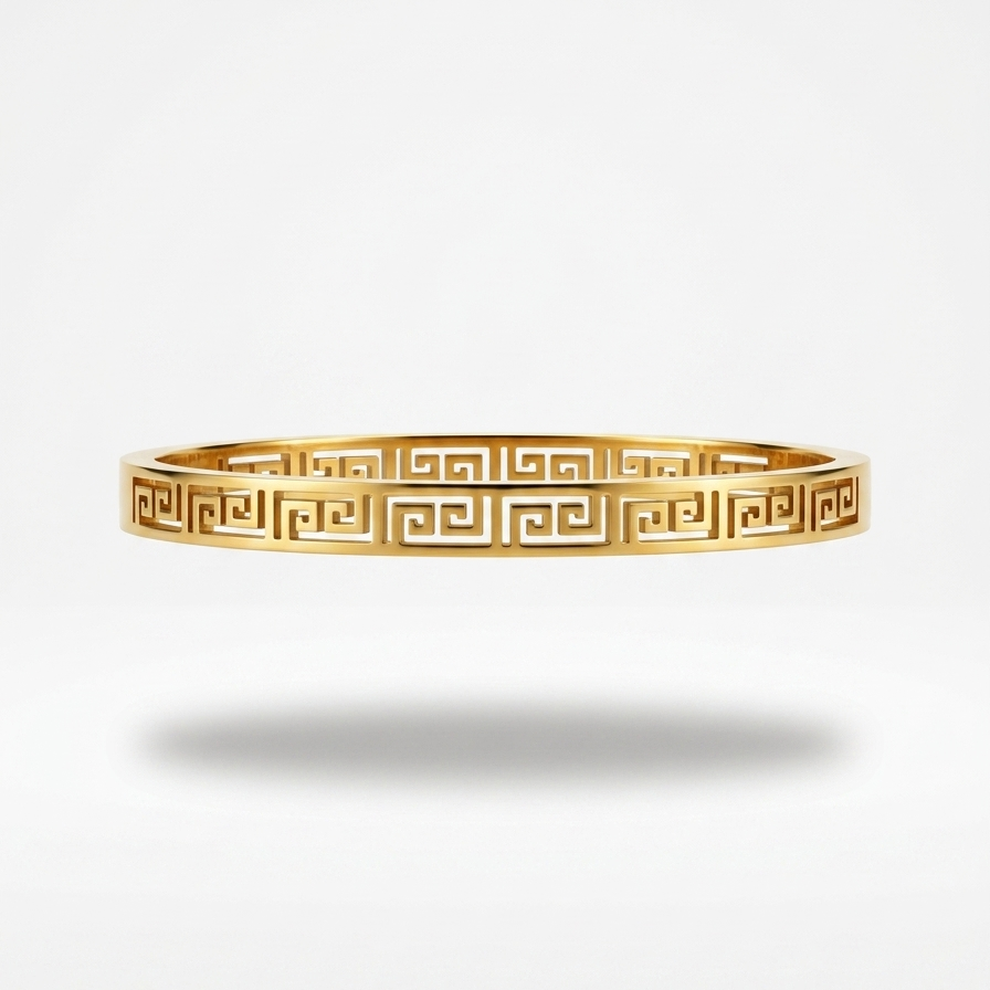 18kt gold plated, anti-tarnish oval bangle bracelet with cut-out Greek Key pattern floating on white background.