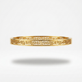 18kt gold plated, anti-tarnish oval bangle bracelet with cut-out Greek Key pattern floating on white background.
