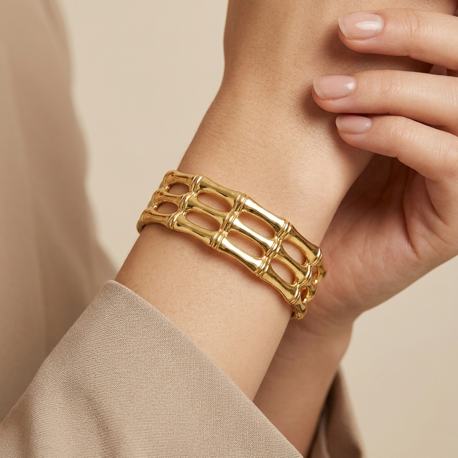A model worn 18kt gold plated, waterproof cuff bracelet with openwork bamboo design.