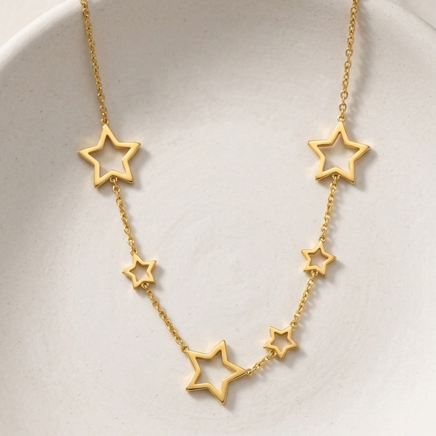 18kt gold plated celestial star station necklace on a off-white plate.