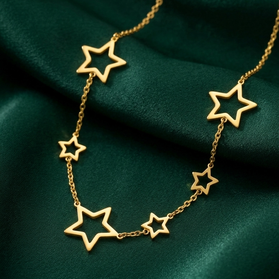 18kt gold plated celestial star station necklace lying on green fabric.