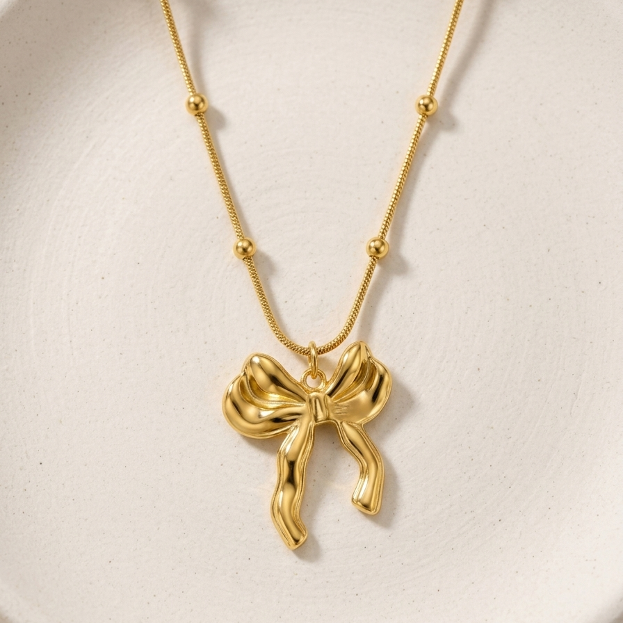 18kt gold plated 3D puffed bow pendant necklace on white background.