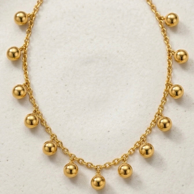 18kt gold plated necklace with spherical beads on a light background.