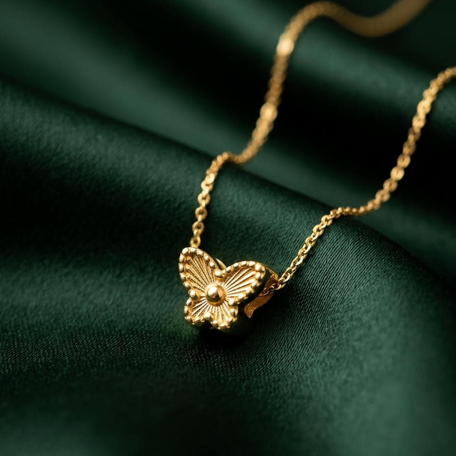 Gold butterfly necklace on a dark green fabric background