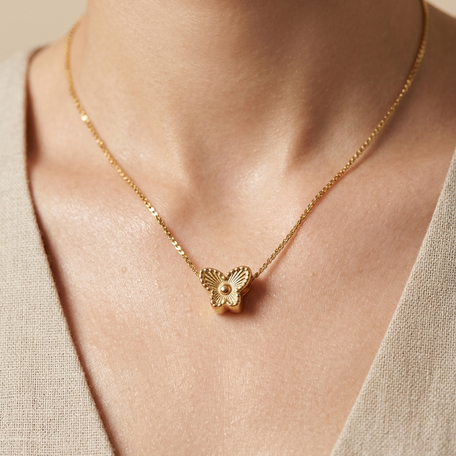 18kt gold necklace with a butterfly pendant worn by a person against a neutral background.