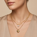 Double layered 18kt gold plated necklace with crystal solitaire and puffy heart pendant wear a model with neutral background.