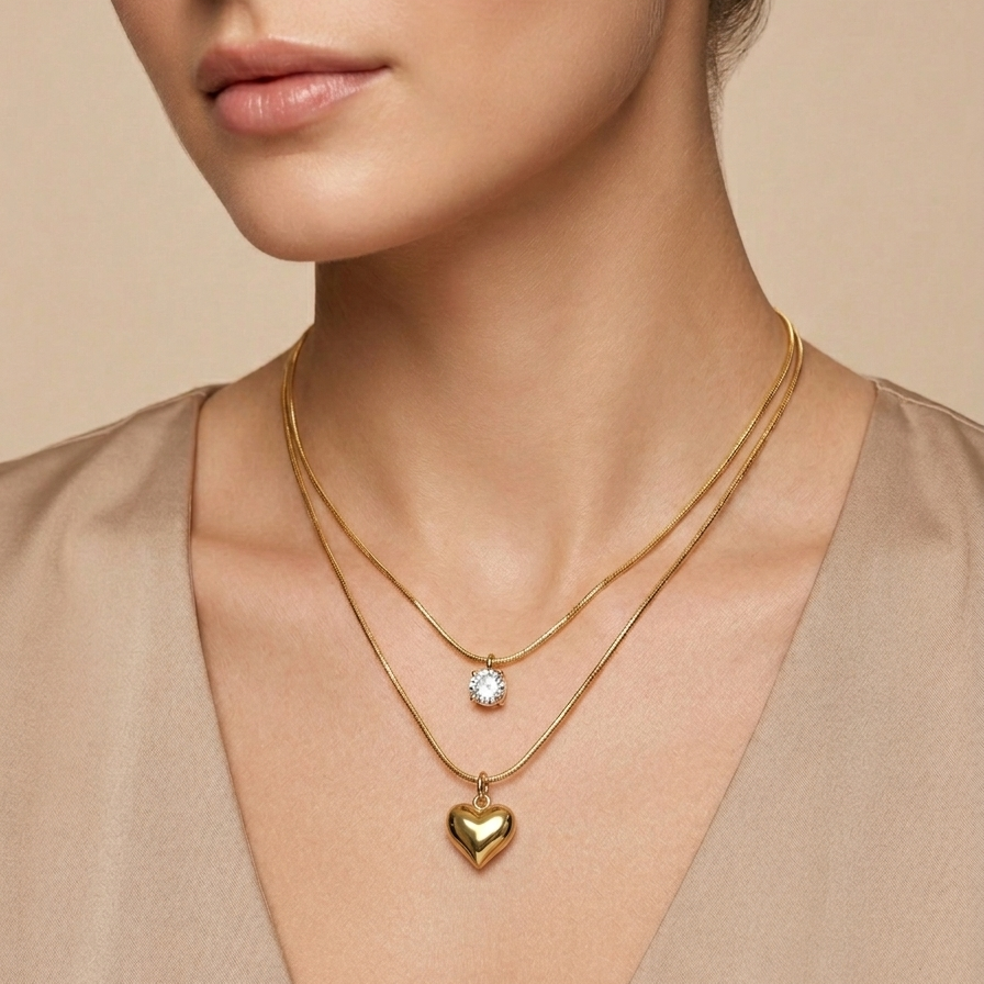 Double layered 18kt gold plated necklace with crystal solitaire and puffy heart pendant wear a model with neutral background.