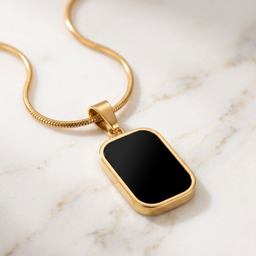 18kt gold plated reversible day and night pendant necklace showing black side on marble surface.