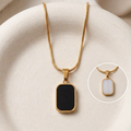 18kt gold plated reversible day and night pendant necklace showing both side on surface.