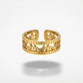 A gold-toned open bangle ring with a textured, ribbed outer band and star-shaped cutouts, shown floating on a light gray background with a soft shadow underneath.