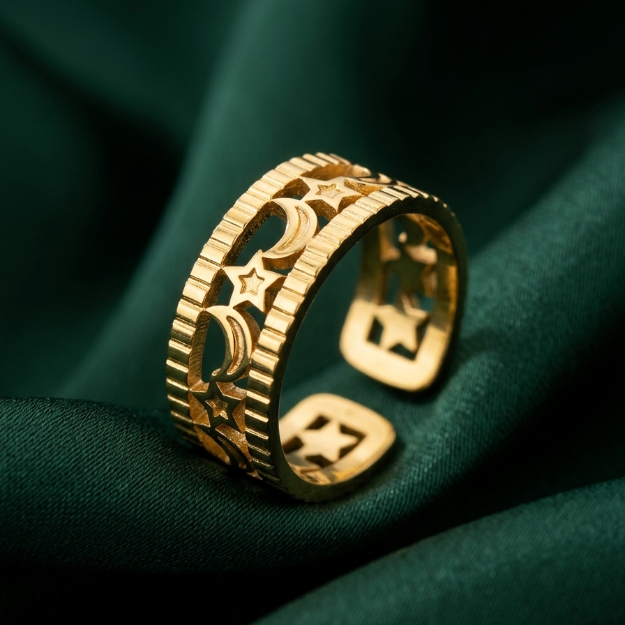 A gold-toned open ring band featuring raised geometric and star-like motifs, photographed on draped dark green fabric.