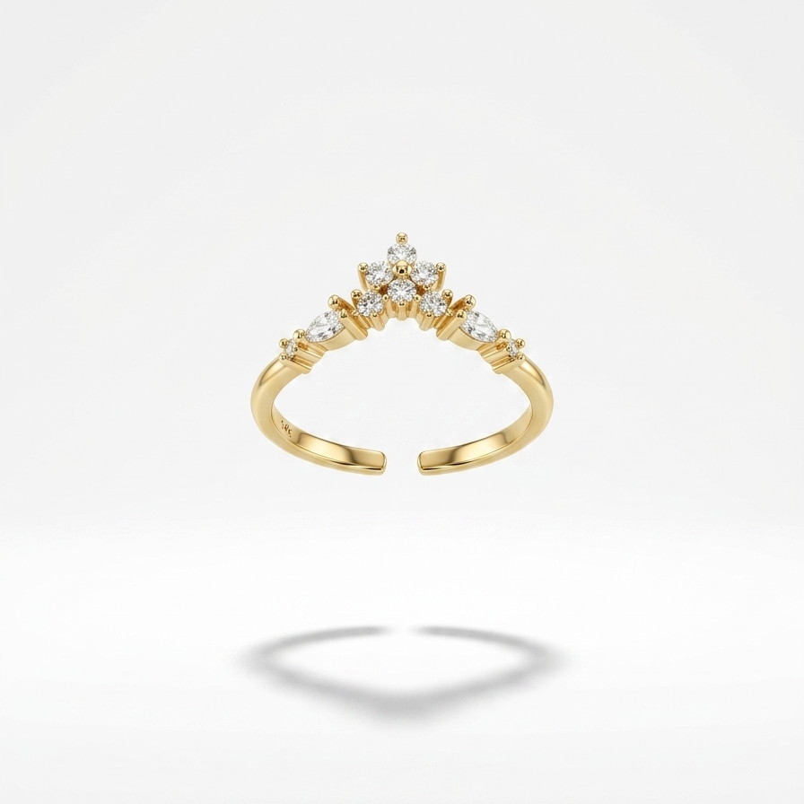 A gold ring with a split band and a small cluster of clear stones at the top, flanked by smaller side stones, shown on a light gray background with a soft shadow below.