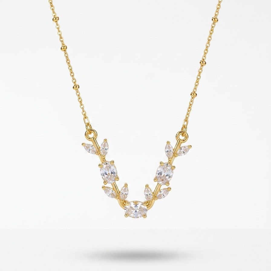 A delicate gold necklace featuring a V-shaped pendant with clear marquise-cut gemstones arranged in a leaf or vine motif, displayed against a clean white background.