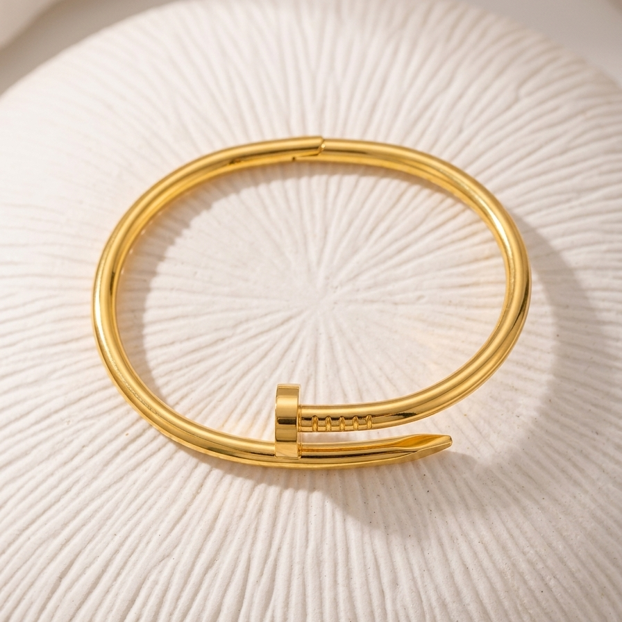18kt gold plated nail cuff bracelet on a textured white surface.