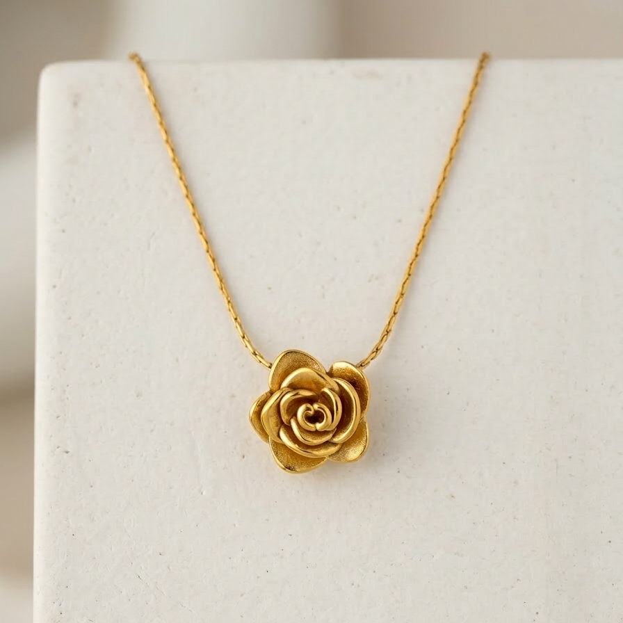 18k gold plated necklace featuring a detailed, sculpted 3D rose pendant on a snake chain, resting on a matte white block.