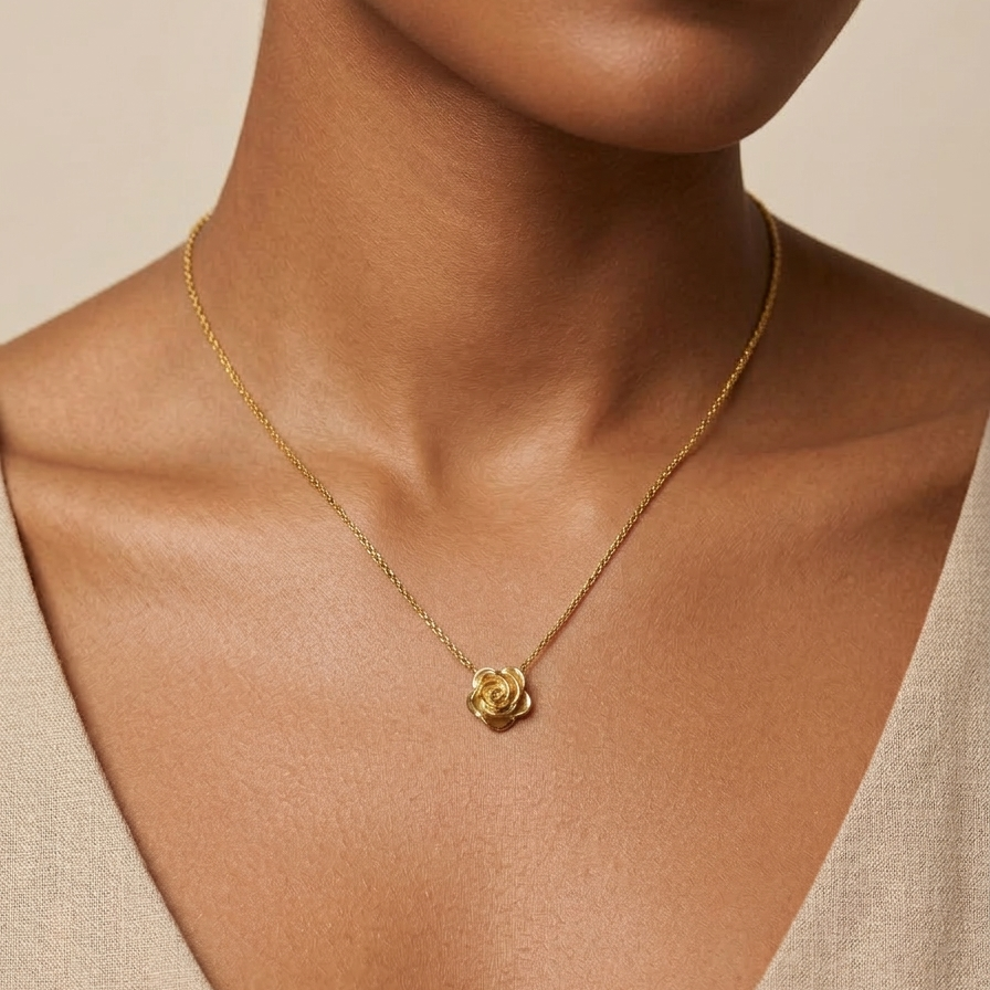 18k gold plated necklace featuring a detailed, sculpted 3D rose pendant on a snake chain, resting on a matte white block on a person with a neutral background