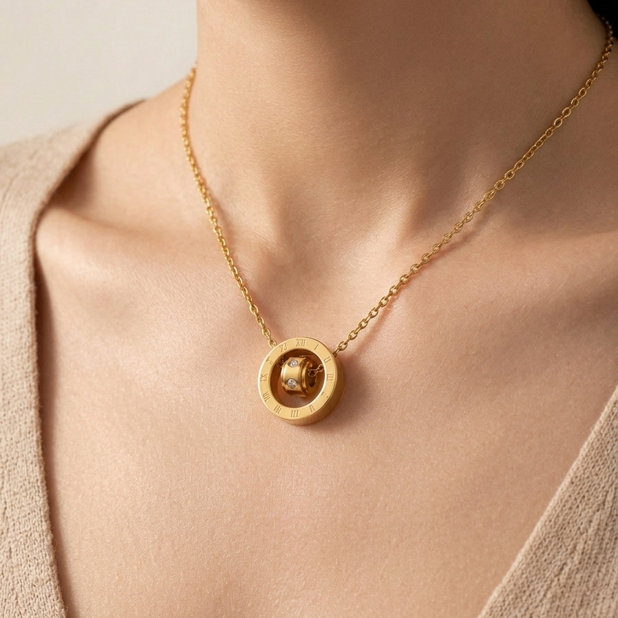 18k gold plated necklace featuring a circular pendant engraved with Roman numerals and a spinning inner barrel accented with CZ diamonds on a person wearing a beige top.