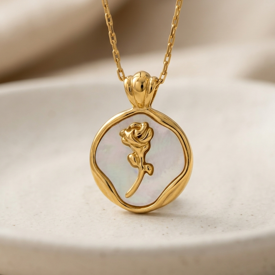 Close up of a 18k gold plated medallion necklace featuring a mother of pearl inlay and a raised golden rose motif in the center.