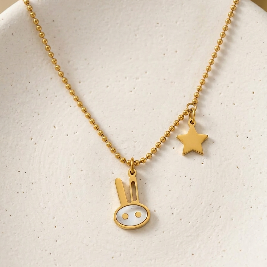 18k gold plated beaded chain necklace featuring a minimalist bunny charm with pearl inlay and a small golden star charm.