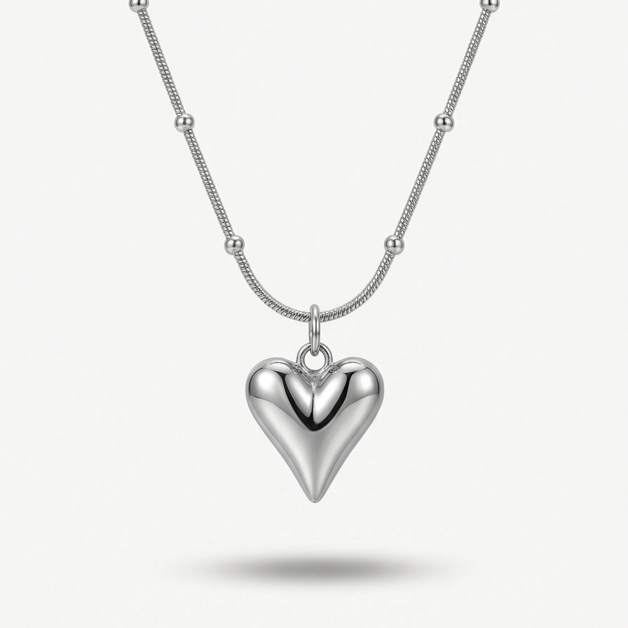 Silver-tone rhodium plated necklace featuring a smooth, 3D puffy heart pendant suspended on a delicate beaded satellite chain.