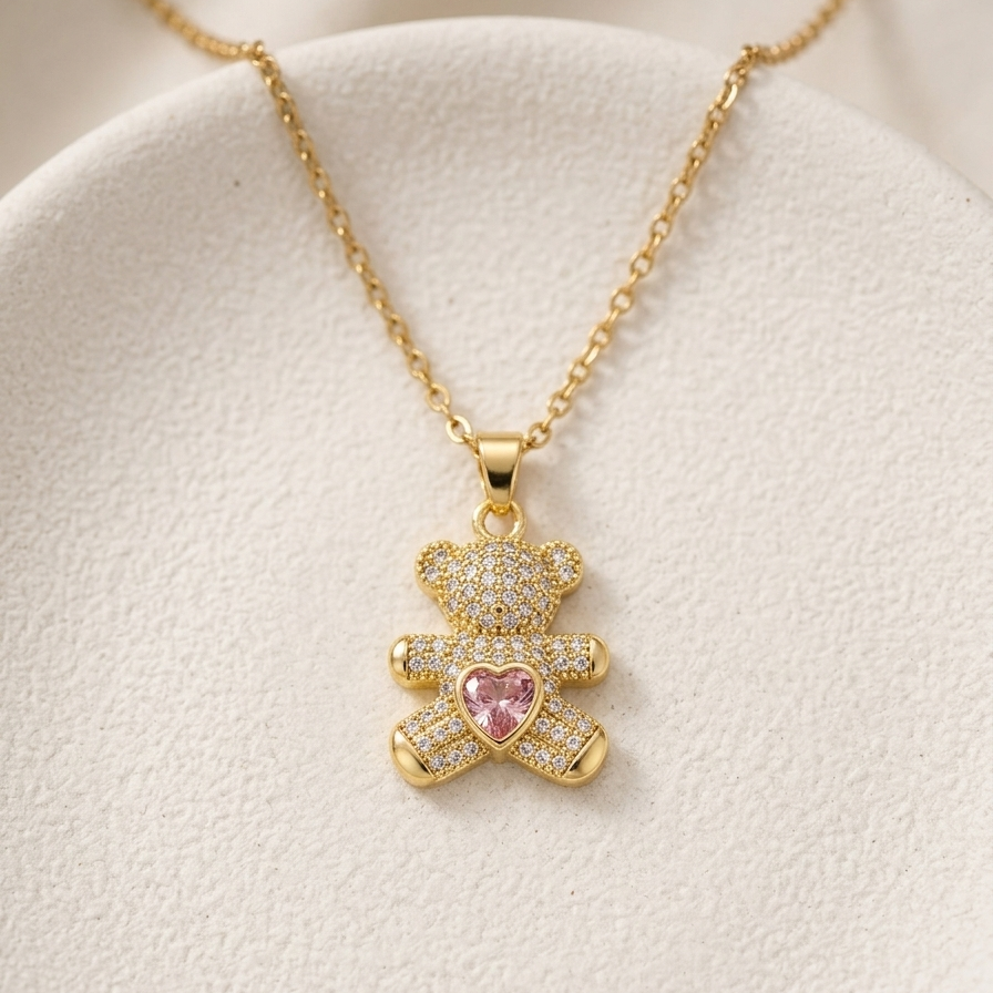18k gold plated teddy bear pendant necklace fully encrusted with clear CZ diamonds, featuring a pink heart-shaped crystal in the center.