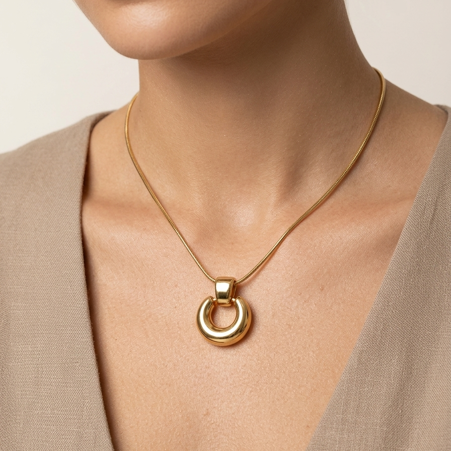 18k gold plated necklace featuring a thick, chunky donut-shaped hoop pendant suspended on a sleek snake chain worn by a person against a neutral background