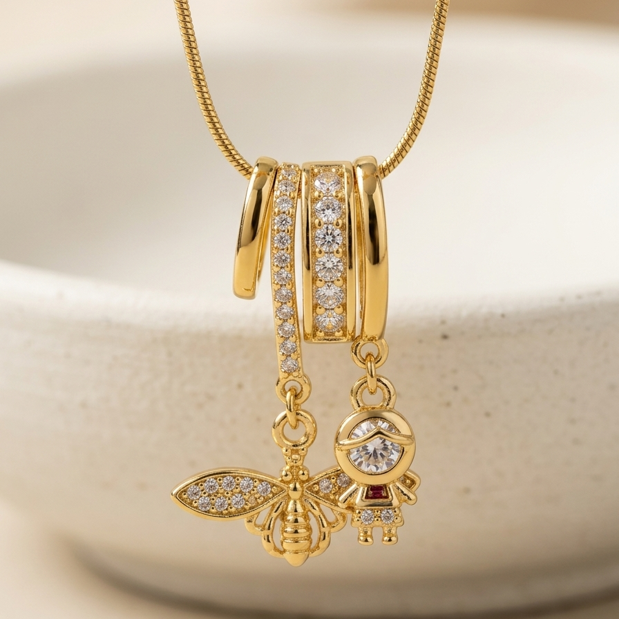 18k gold plated necklace featuring an intricate diamond-encrusted sliding bail holding a detailed golden bee charm and a small figure charm.