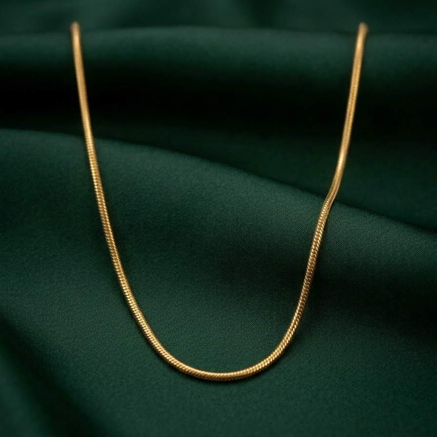 18k gold plated foxtail layering chain showing intricate woven V-shaped links and an adjustable extender clasp. on a green fabric background