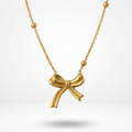 18k gold plated necklace featuring a sculpted, fluid ribbon bow pendant suspended on a delicate beaded satellite chain.