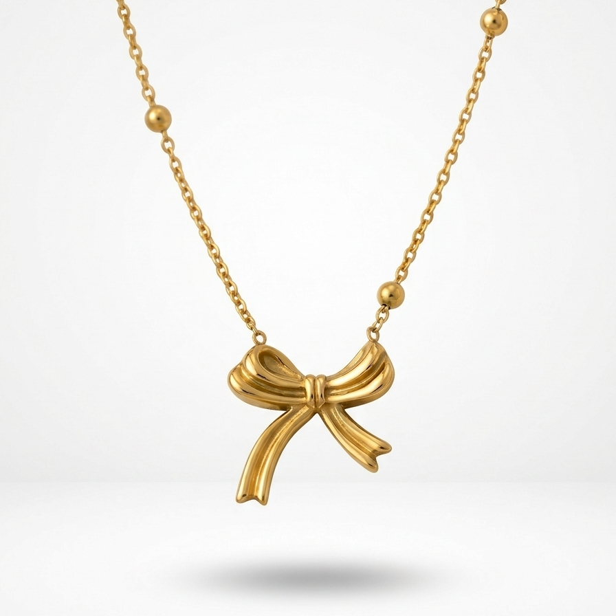 18k gold plated necklace featuring a sculpted, fluid ribbon bow pendant suspended on a delicate beaded satellite chain.