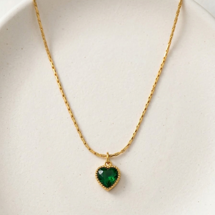 18k gold plated necklace featuring a deep emerald green heart-shaped crystal pendant with a textured golden border, on a delicate chain.