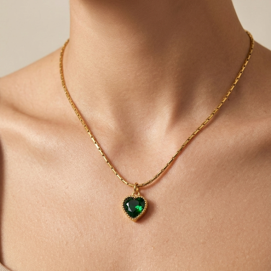 18k gold plated necklace featuring a deep emerald green heart-shaped crystal pendant with a textured golden border, on a delicate chain.