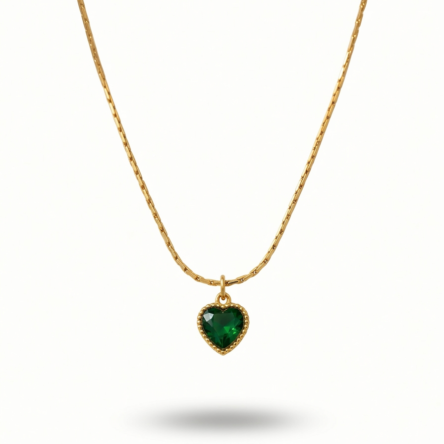18k gold plated necklace featuring a deep emerald green heart-shaped crystal pendant with a textured golden border, on a delicate chain.