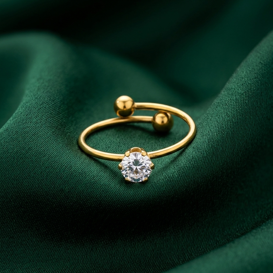 an 18k gold plated minimalist adjustable ring featuring a single CZ diamond and two small gold spheres, resting on a deep green cloth.