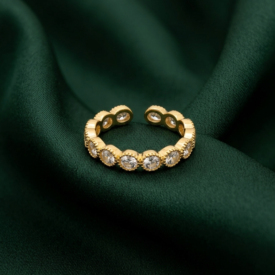 an 18k gold plated eternity band ring featuring a row of sparkling CZ diamonds with vintage beaded edges, resting on a deep green fabric.